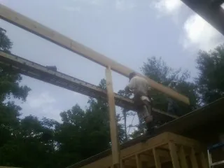 Carpenter setting a ridge beam over a new addition frame — Ice Dam Removal by Roofing Brothers in Nerstrand
