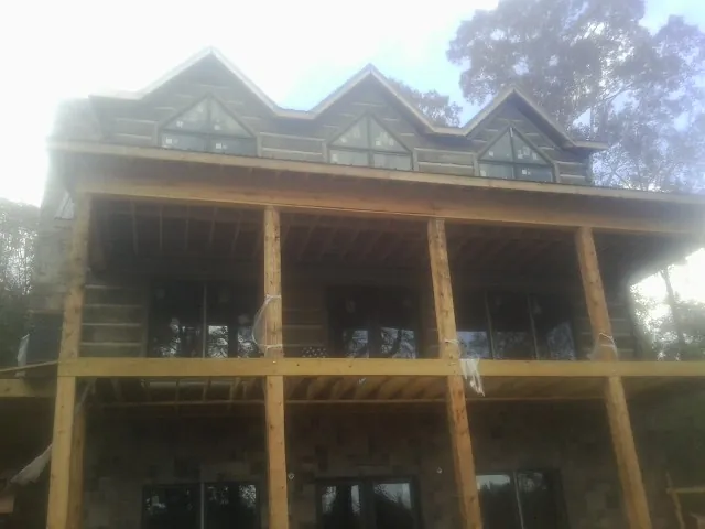 Dormers and porch framing on a large log home under construction — Roof Coating work by our crew in Nerstrand