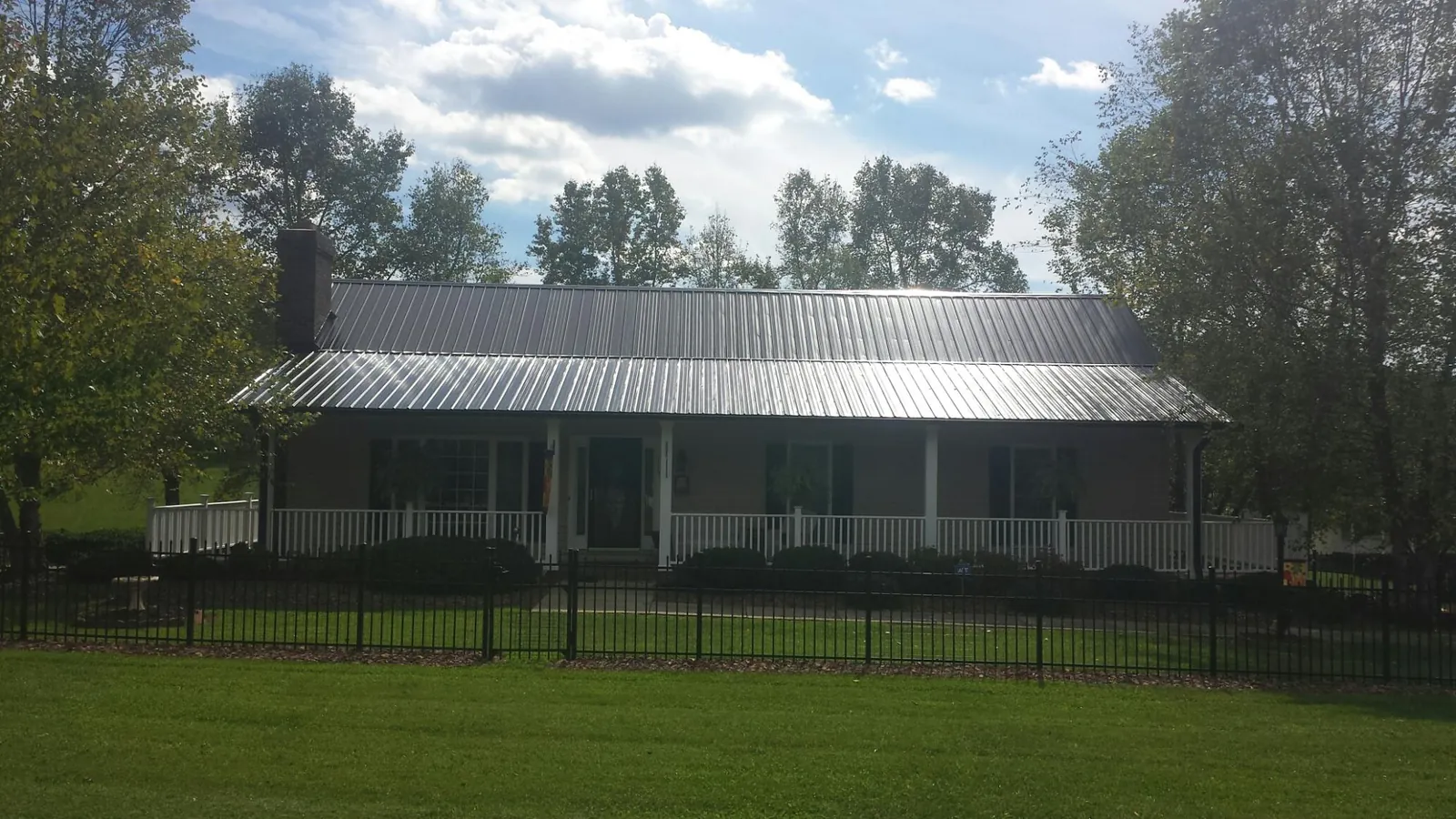 Gray metal roof on a brick ranch with a full width front porch — Gutter Guard Installation work by our crew in Nerstrand