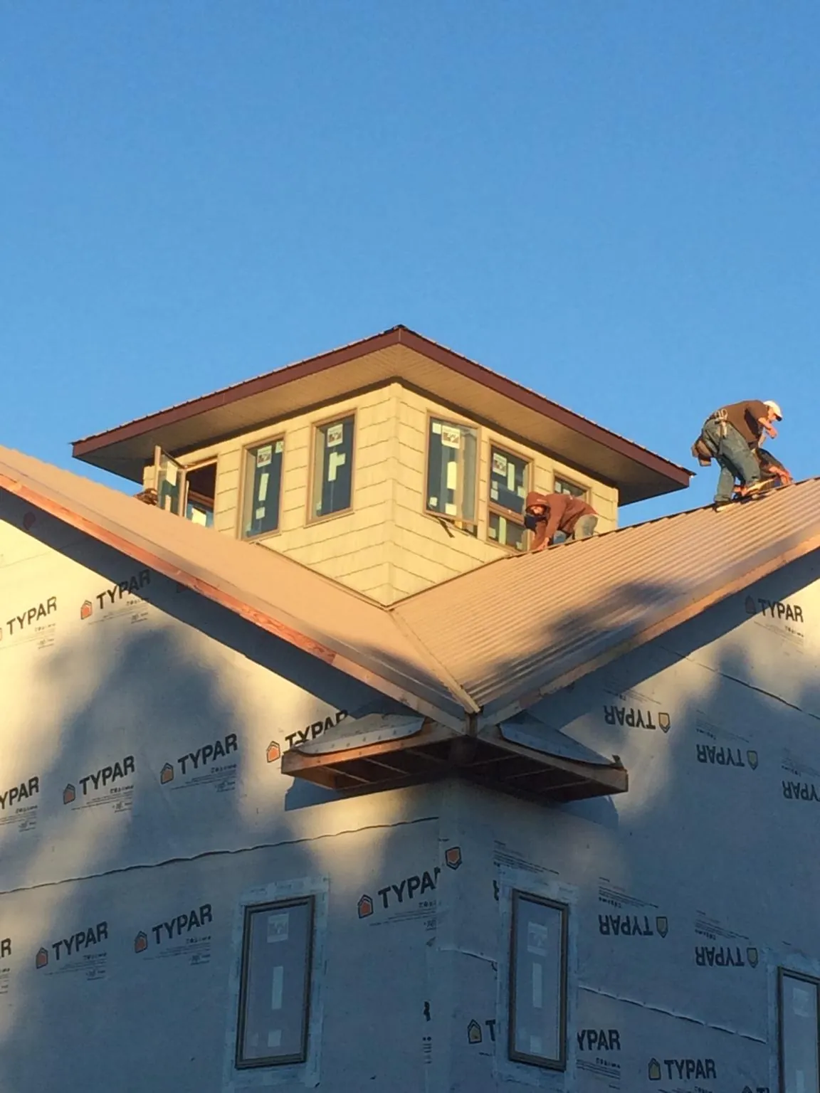 Roofers working around a rooftop cupola on a new metal roof at sunset — Roof Waterproofing in Nerstrand by Roofing Brothers